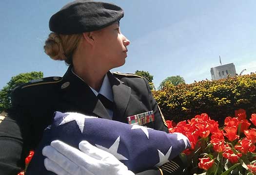 Active duty soldier with folded flag at White Chapel Memorial Park.